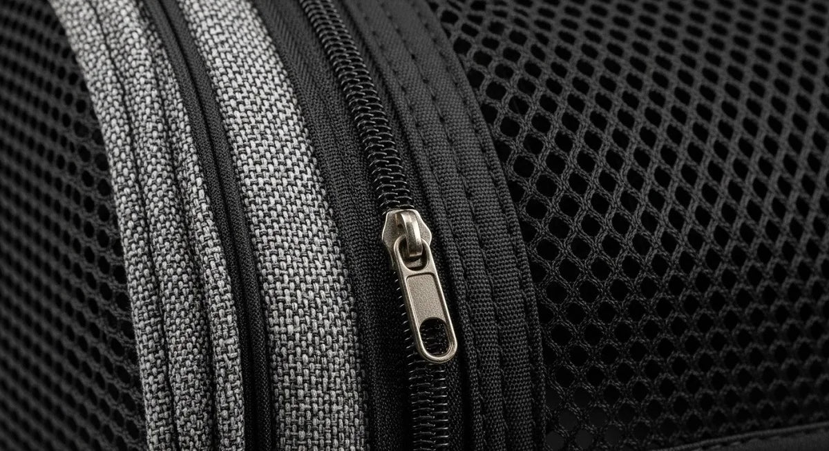 Close-up of a black luggage bag’s zipper and mesh fabric with gray accents visible.